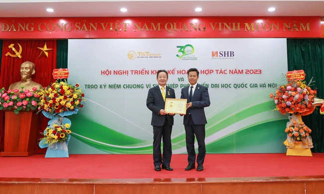 GS.TS Lê Quân (bên phải) trao kỷ niệm chương vì sự nghiệp phát triển ĐHQGHN cho doanh nhân Đỗ Quang Hiển.
