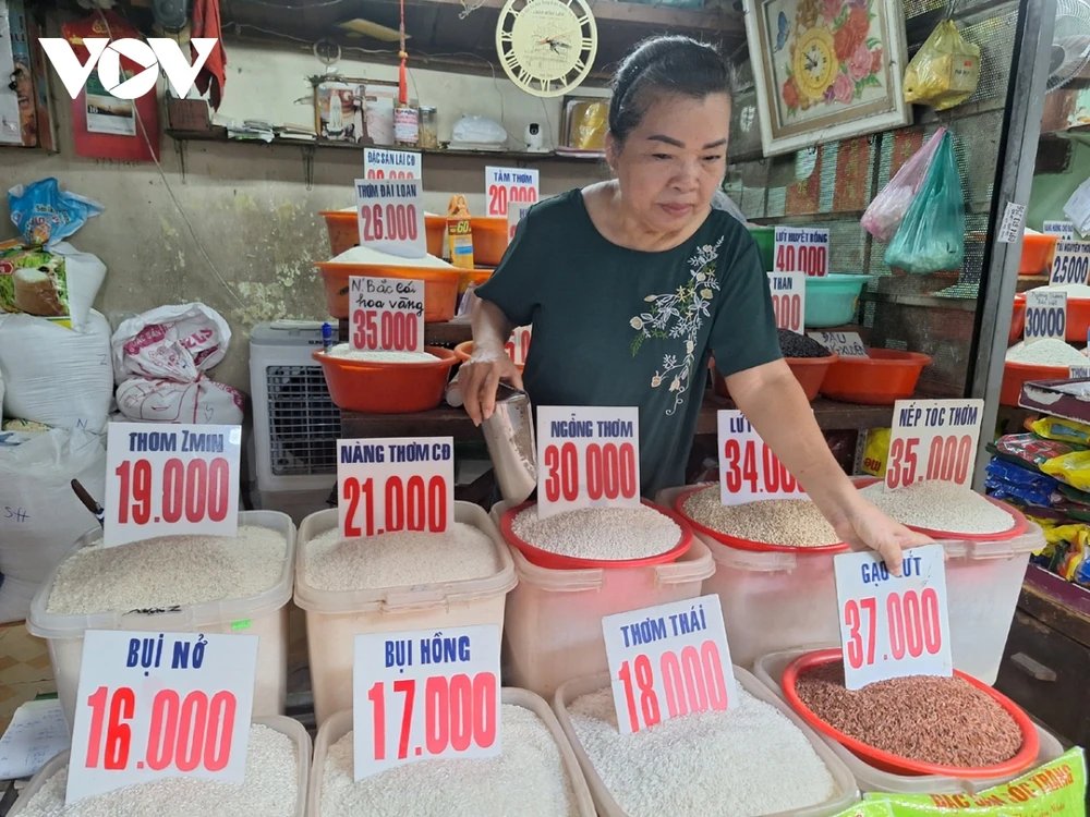 Chị Cúc bán gạo ở chợ Thị Nghè, quận Bình Thạnh đang thay bảng mới khi giá đầu vào tăng - Ảnh: Lệ Hằng 