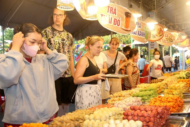 Nhiều du khách quốc tế tham quan không gian trưng bày giới thiệu sản phẩm du lịch, sản phẩm OCOP và ẩm thực đường phố tại một điểm du lịch đêm ở Bình Thuận. (Ảnh: Nguyễn Thanh/TTXVN)