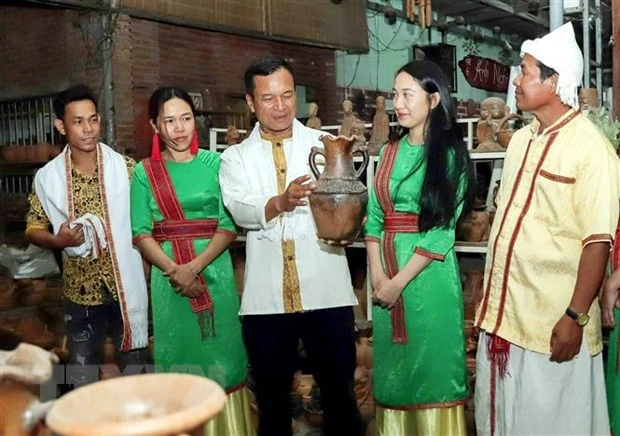 Ông Đàng Chí Quyết giới thiệu với du khách về gốm truyền thống của làng nghề. (Ảnh: TTXVN phát)