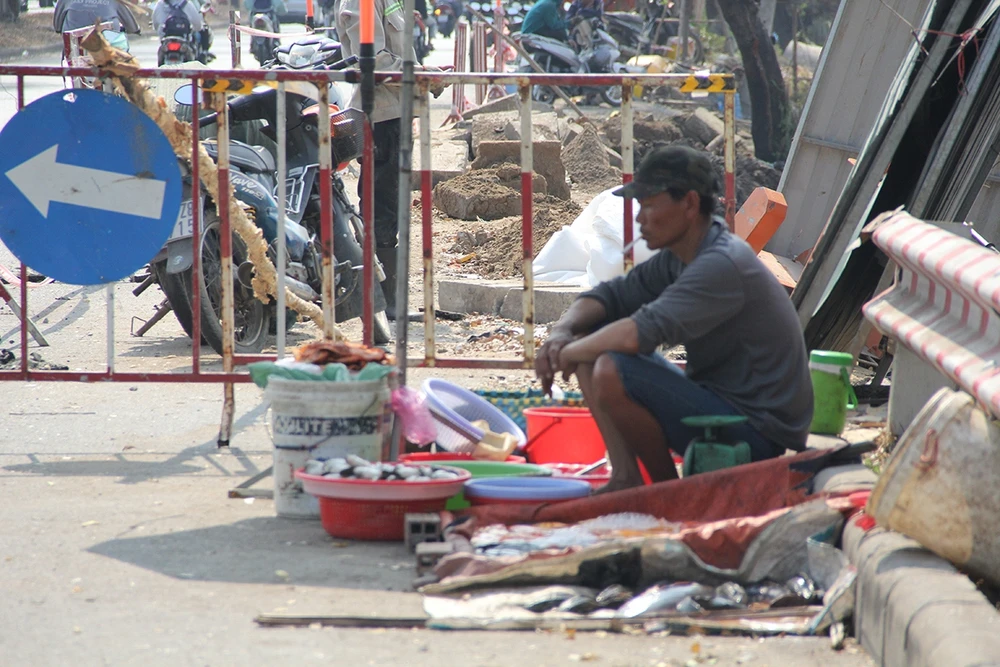 Một người đàn ông ngồi bán cá ở ven đường giữa trưa (Ảnh: Hoàng Minh)