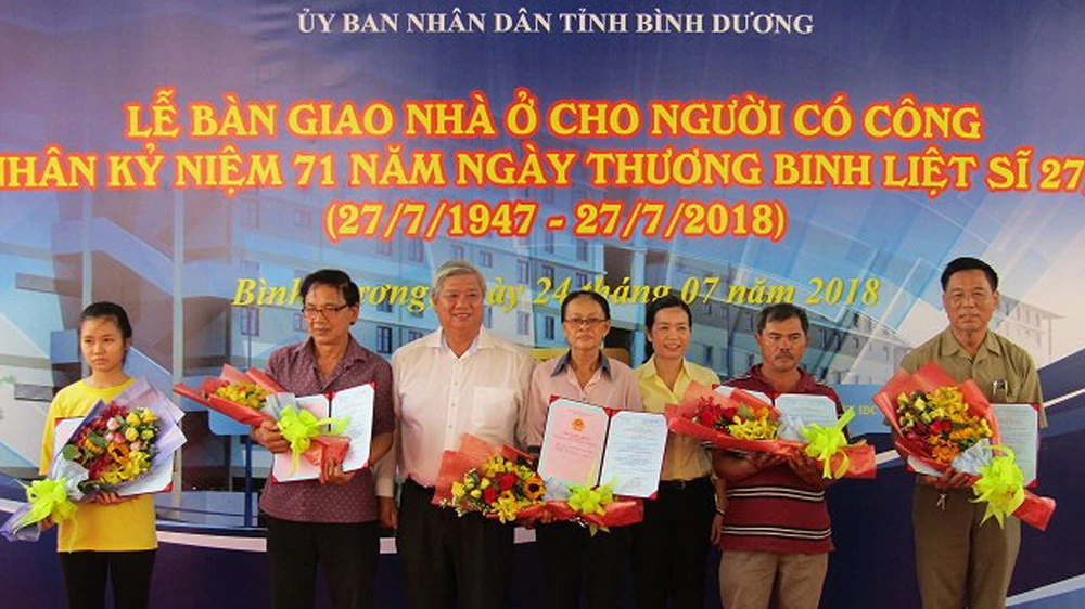 Ông Đặng Minh Hưng (thứ 3 từ trái qua) tặng hoa cho các cá nhân được nhận nhà