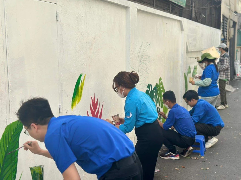 Đoàn viên của phường Đa Kao tham gia vẽ lại mảng tường. Ảnh: CHÍ THẠCH