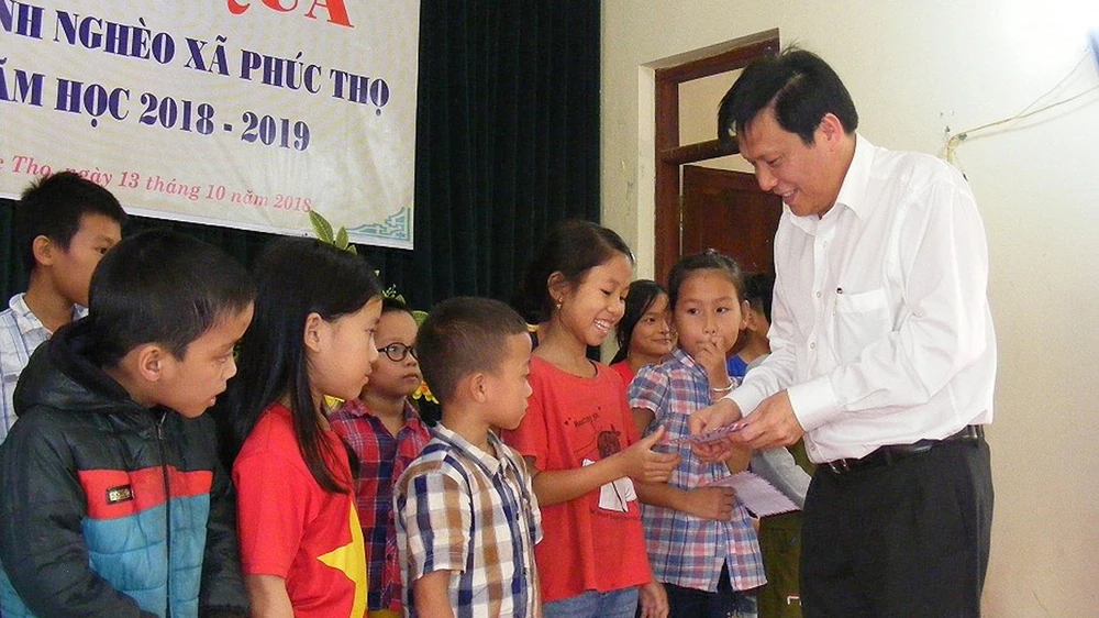 Thay mặt Báo SGGP, Phó Tổng Biên tập báo SGGP Nguyễn Ngọc Anh trao quà cho các cháu học sinh nghèo học giỏi xã Phúc Thọ