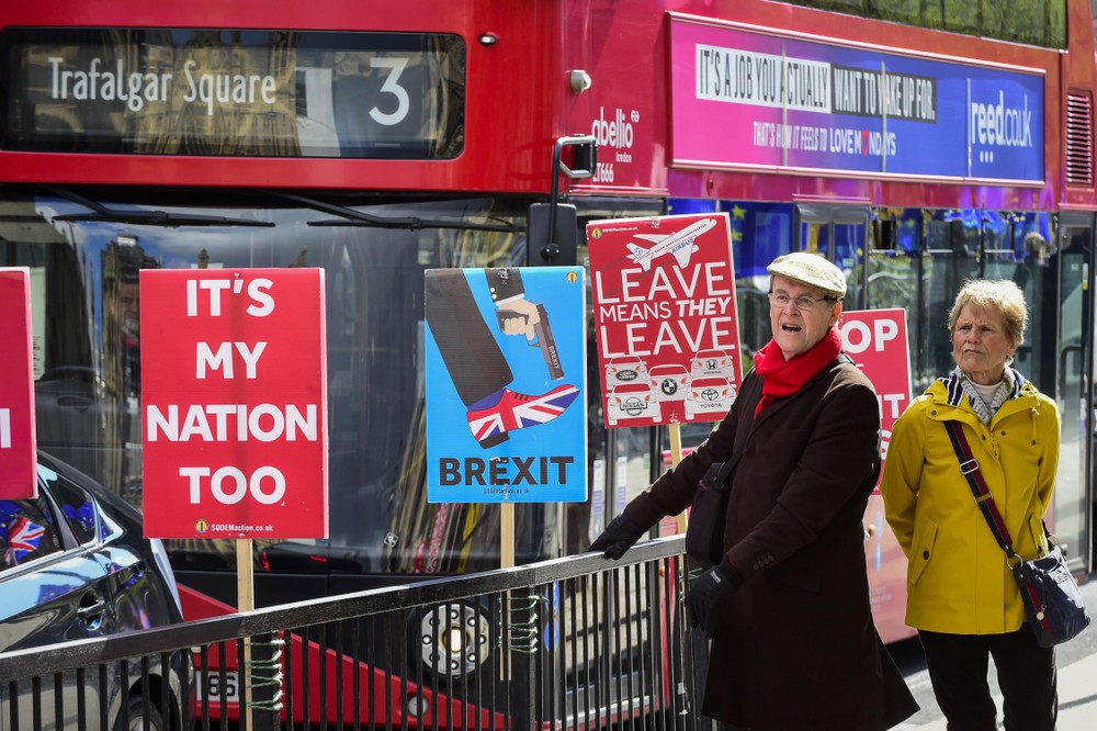 在倫敦議會大廈外，人們從反對“脫歐”的標語牌前走過。