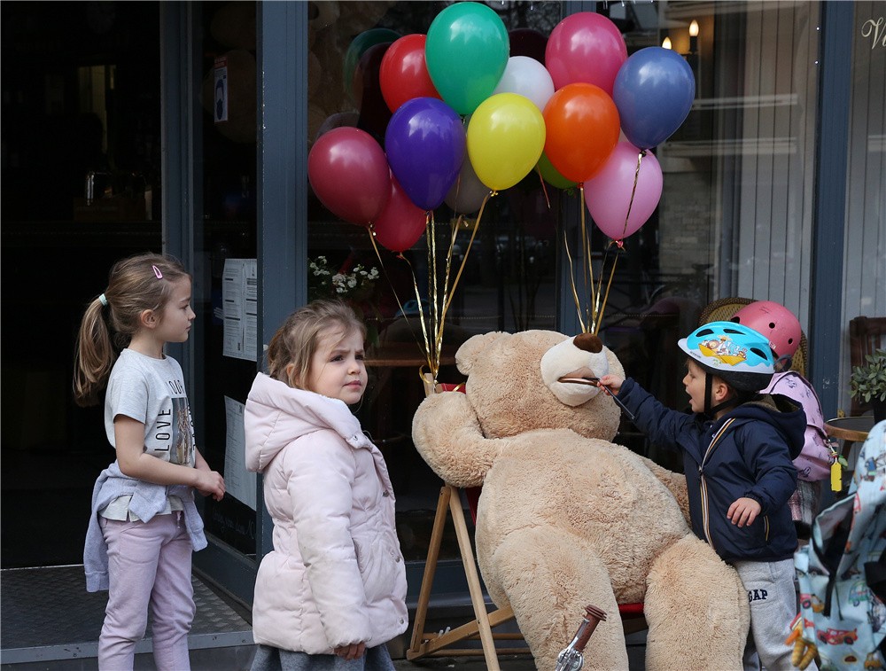 孩子們被法國巴黎街頭一家餐館外的玩具熊吸引。