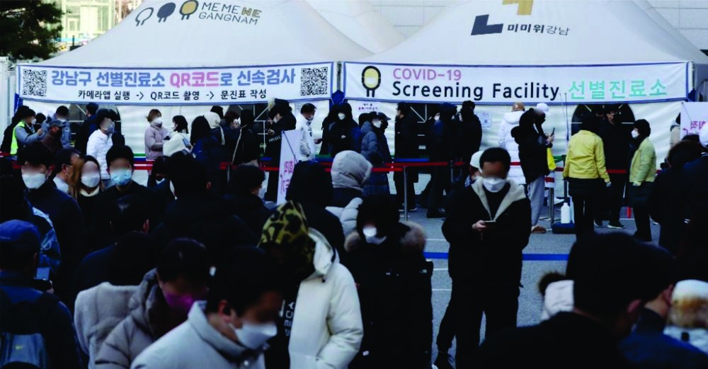 人們在韓國首爾江南區一處新冠檢測點排隊等待核酸採樣。
