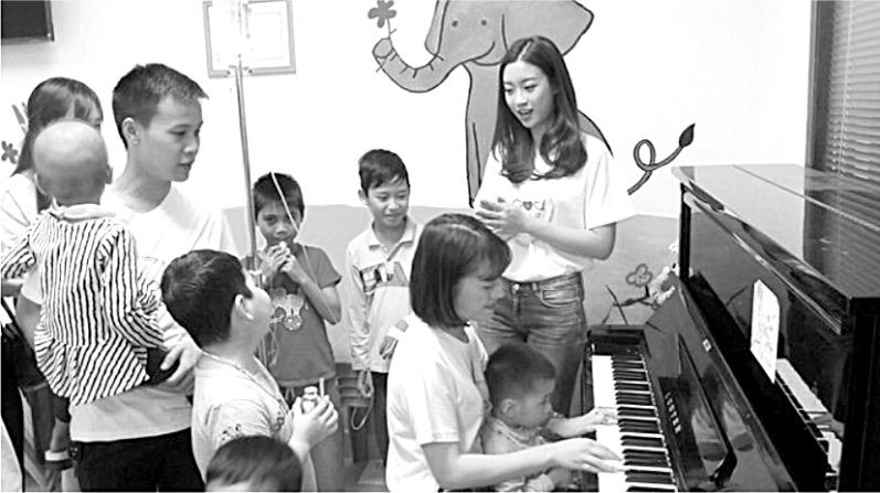 歌手黎玄英（坐者）與2016越南小姐 杜美玲於4月2日中午，在中央血液學與輸血院同病童邊彈邊唱。