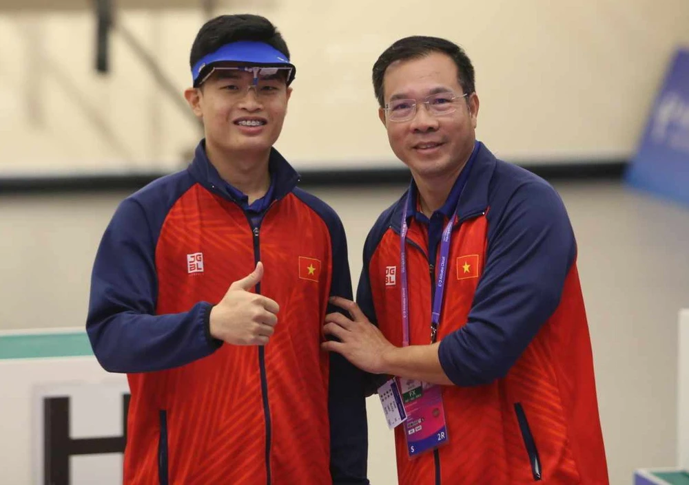 Phạm Quang Huy và HLV Hoàng Xuân Vinh sau khi giành HCV tại ASIAD 19. Ảnh: LƯỢNG LƯỢNG