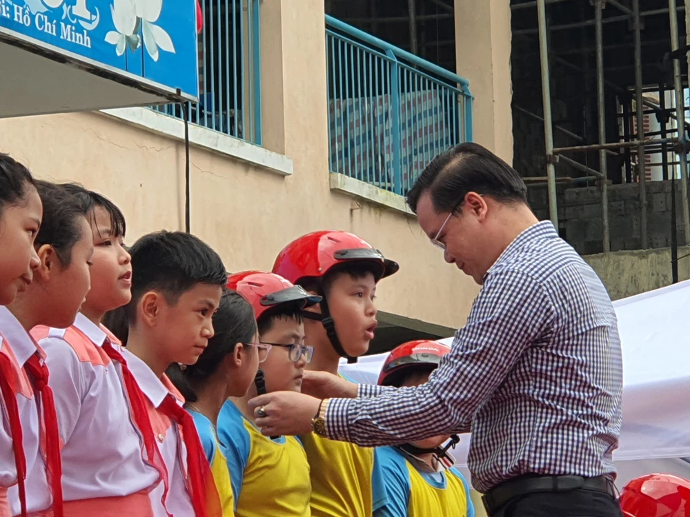 Thầy Trần Nguyễn Minh Thành trao tặng mũ bảo hiểm cho các em học sinh lớp 5 có hoàn cảnh gia đình khó khăn