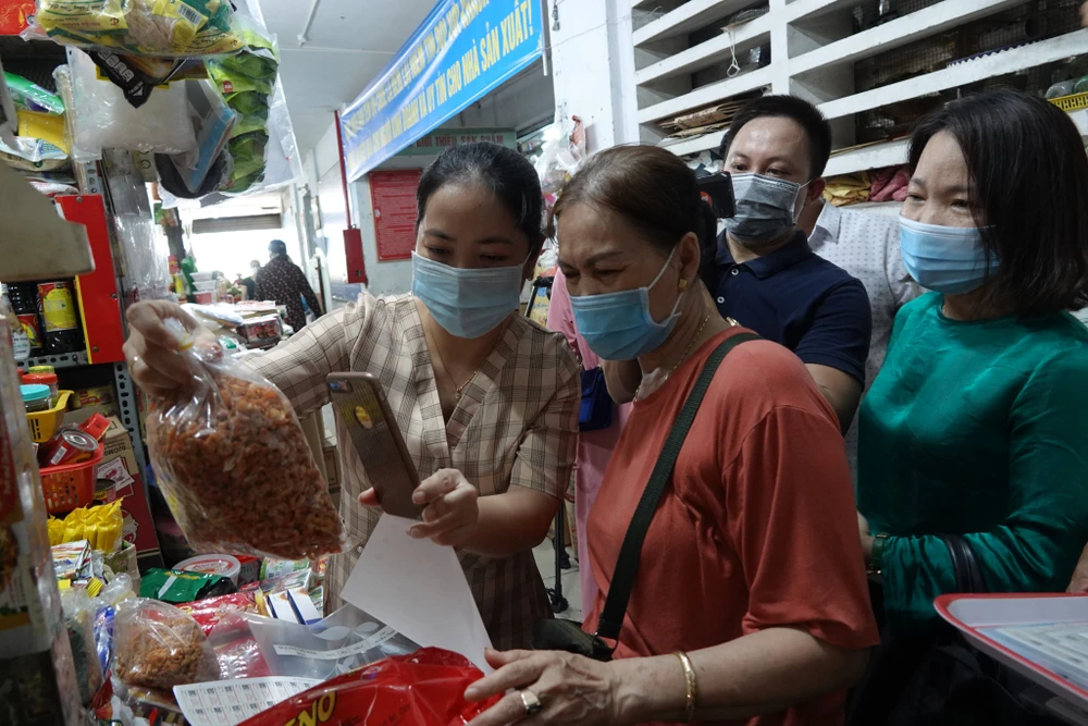 Thành viên Ban quản lý các chợ quận Hải Châu hướng dẫn người dân quét mã QR Code trên điện thoại thông minh