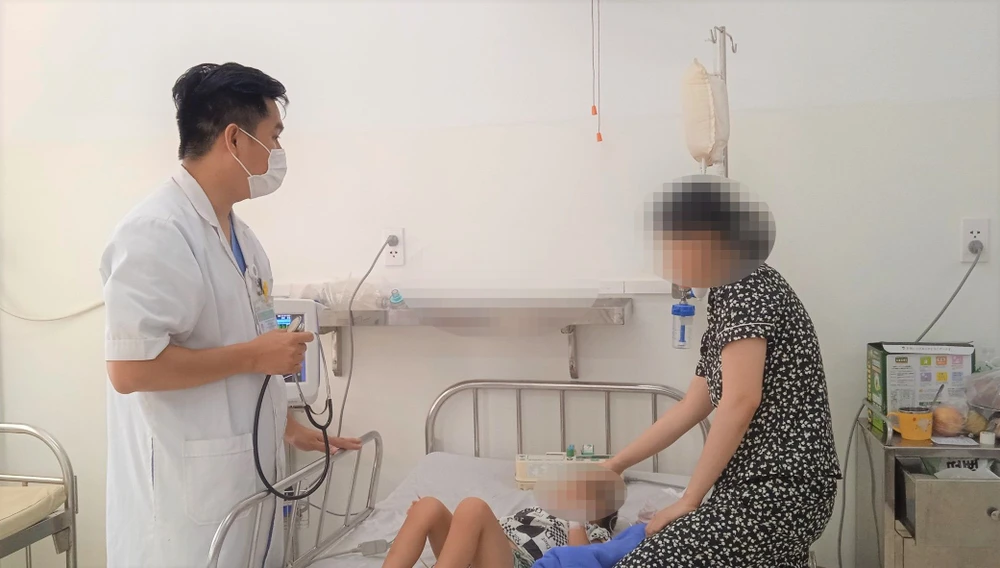 Bác sỹ Nguyễn Hải Thịnh đang khám bệnh cho con của chị Lê Thị Ngọc Châu. Ảnh: XUÂN QUỲNH