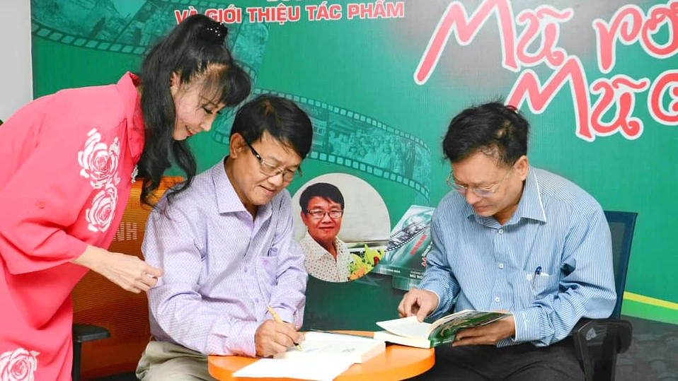 Nhà báo Huỳnh Dũng Nhân ký tặng sách cho độc giả trong buổi ra mắt tác phẩm "Chúng tôi - Một thời mũ rơm, mũ cối"