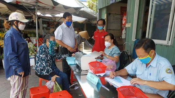 Người đi chợ Bình Thới khai báo y tế trước khi nhận phiếu đi chợ theo thứ tự trong đợt giãn cách vừa qua