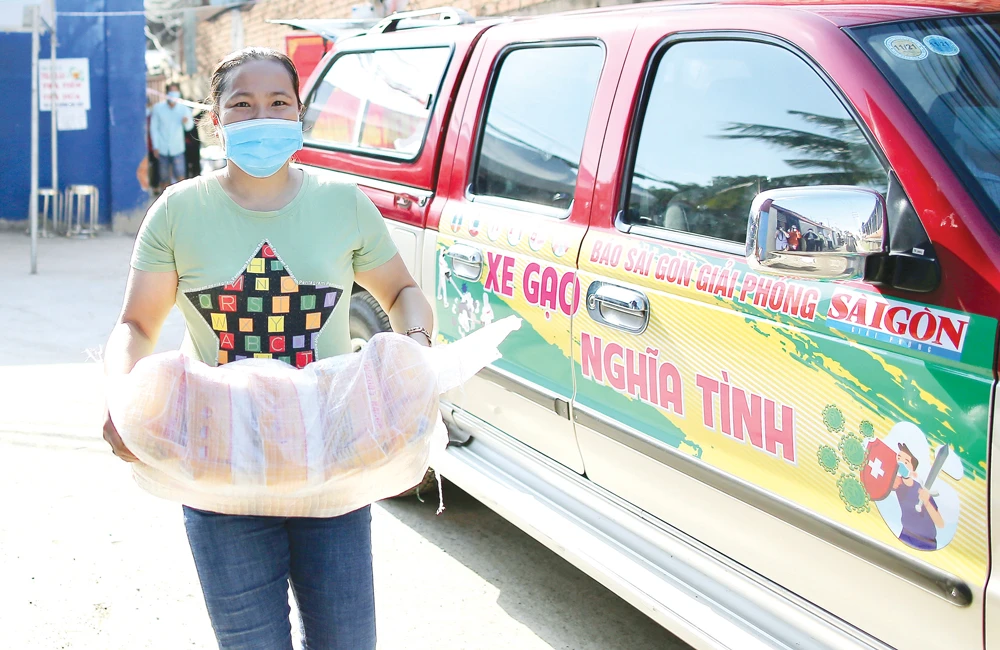 Người dân hẻm 54 Hồ Học Lãm, phường 16 (quận 8) nhận gạo hỗ trợ từ Báo SGGP. Ảnh: DŨNG PHƯƠNG