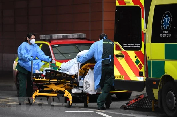 Nhân viên y tế chuyển bệnh nhân Covid-19 tới bệnh viện ở London, Anh. Ảnh: AFP/TTXVN