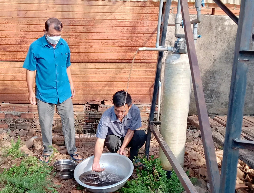 Ông Nguyễn Văn Hải (bên phải) vận hành hệ thống máy lọc nước sinh hoạt cho gia đình