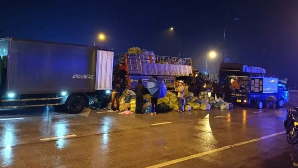 Người dân giúp đỡ tài xế bốc hàng tấn rau củ quả từ xe tải gặp nạn sang xe khác trong đêm tối mưa, lạnh