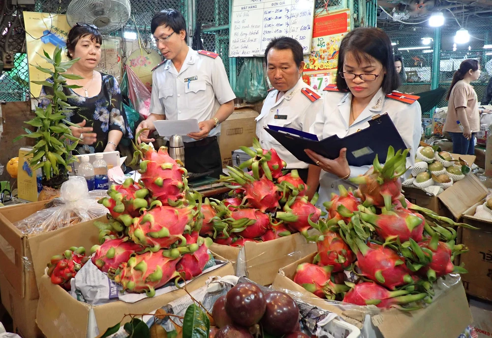 Thanh tra Ban Quản lý An toàn thực phẩm TPHCM kiểm tra một hộ kinh doanh trái cây tại chợ đầu mối nông sản Thủ Đức. Ảnh: HOÀNG HÙNG
