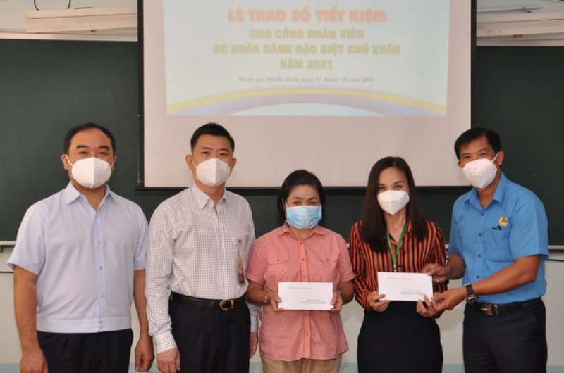 市工會基層社會工作中心主任阮文光（右一）向受新冠疫情影響 的工會會員贈送存摺。