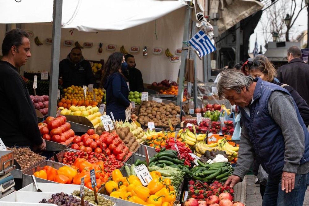 一名男子在希臘雅典一處集市購買蔬菜。