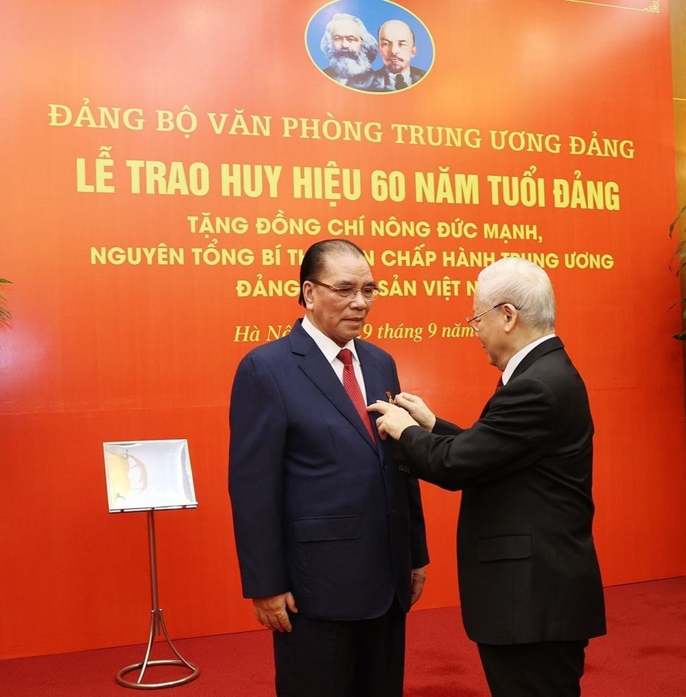 党中央总书记阮富仲向农德孟同志别上纪念章。