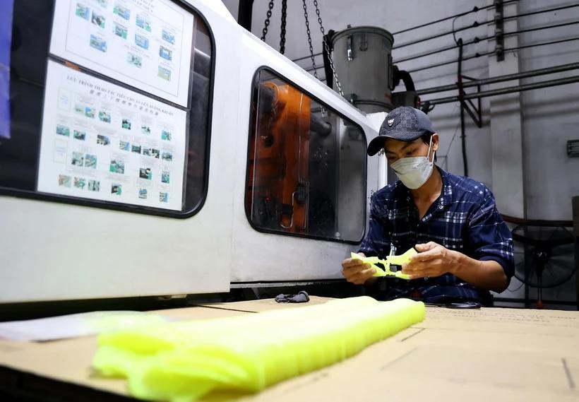 平阳省顺安市的工人正在制作塑料模具来生产皮鞋。