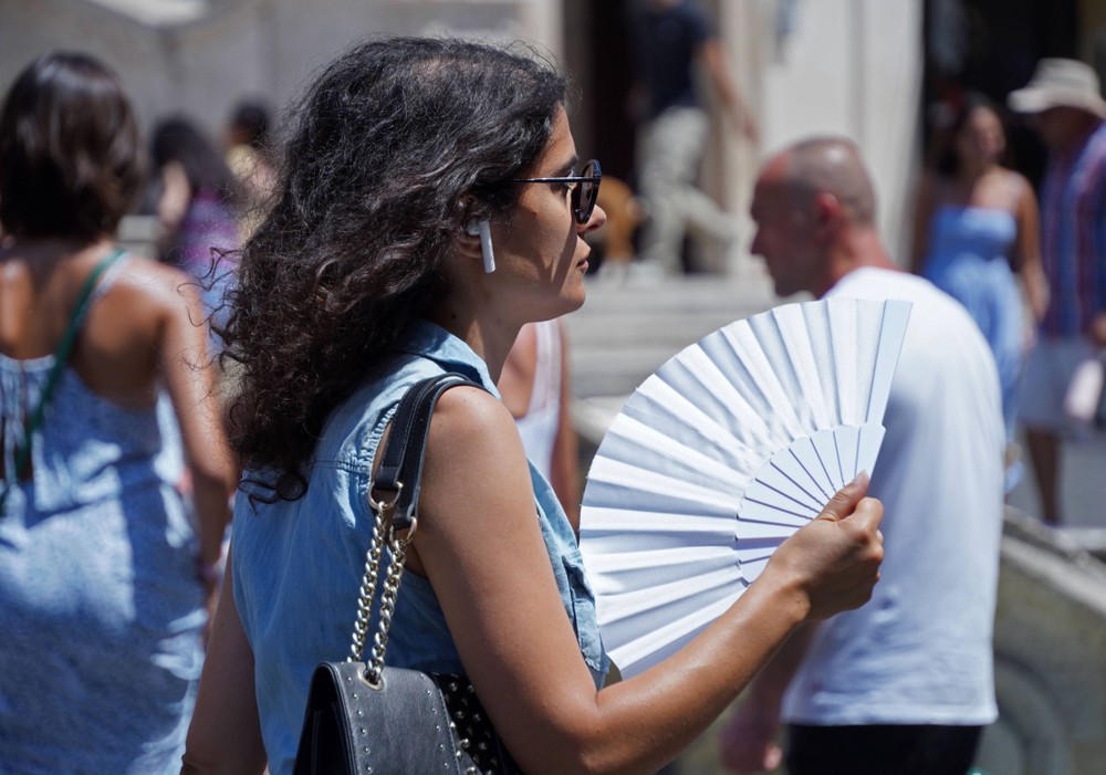 一名女子在意大利罗马街头扇扇子降温。(新华社)