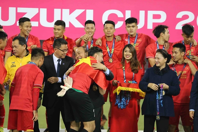 Thủ tướng Nguyễn Xuân Phúc chúc mừng từng thành viên của đội tuyển Việt Nam trên bục trao Cúp vô địch. Ảnh: DŨNG PHƯƠNG