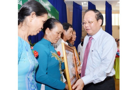 Standing Deputy Secretary of Party Committee of Ho Chi Minh City, Tat Thanh Cang awards the Heroic Vietnamese Mothers title to a mother’s relatives. (Photo: Sggp)