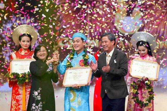 Than Thi Thu ( in black Ao Dai), head of the Ho Chi Minh City Party Committee's Commission for Propaganda and Education, hands over the Golden Bell to Nguyen Van Khoi. (Photo: Sggp)