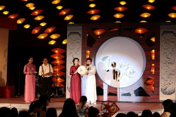 Ms. Tran Mai Anh (in white Ao Dai), represents the Thien Nhan and Friends Fund to receive the donation from the organization board of the Mid-Autumn charity festival. (Photo: Sggp)