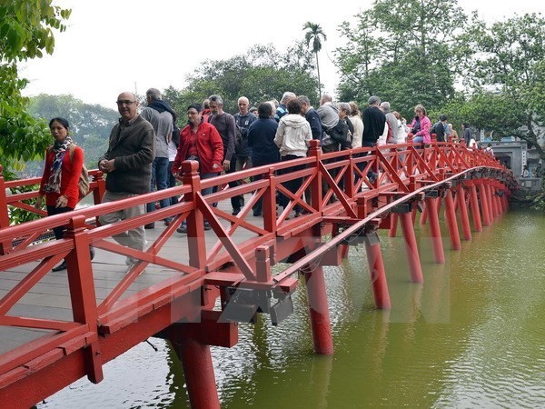 Tourists stand on "The Huc" Bridge, which leads to Ngoc Son Temple on Hoan Kiem Lake in Hanoi (Photo: VNA)