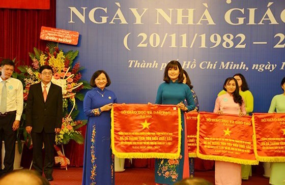 Head of the Department of Propaganda and Training of the HCMC Party Committee Than Thi Thu (in blue Ao Dai) presents the Government’s emulation flag to the City’s Department of Training and Education. (Photo: Sggp)
