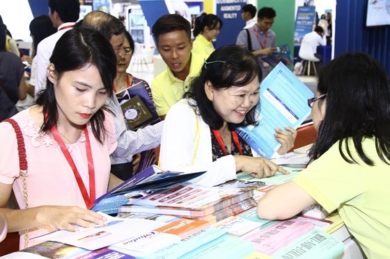 Visitors purchase tours at a display booth. (Photo: Sggp)