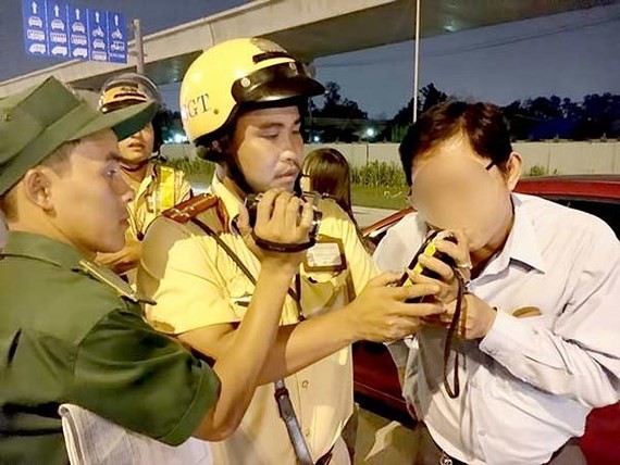 A traffic police officer measures breath alcohol concentration of a driver. (Photo: Sggp)