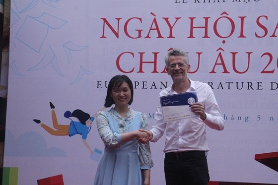 Ambassador Bruno Angelet, Head of the Delegation of the European Union to Vietnam presents a Certificate of Merit to Ly Thuy Vy, one of the winners of a painting competition themed Creative with European Literary Characters. (Photo: Sggp)