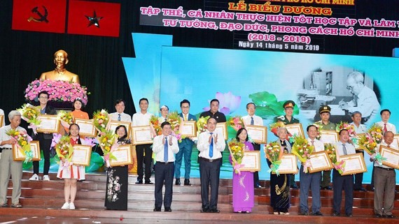 Secretary of HCM City Party Committee Nguyen Thien Nhan and chairman of the municipal People’s Committee Nguyen Thanh Phong present certificates of merit to honored individuals and units. (Photo: Sggp)