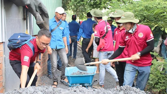 Young volunteers repair a concrete alley in Binh Chanh district. (Photo: Sggp)