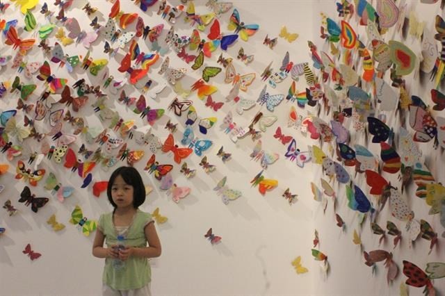Little girl takes a photo with hundreds of colourful butterflies. (Source: VNA)