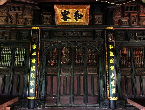 A horizontal lacquered board engraved with characters , “Hoa Dung”, is hung over a door aiming at teaching the family’s members to live in peace with each other.