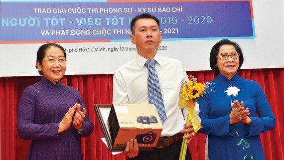 Former deputy Secretary of the HCMC Party Committee, Nguyen Thi Thu Ha (R ); Vice Secretary of the municipal Party Committee, Vo Thi Dung (L ) award the first prize to journalist Minh Anh. 