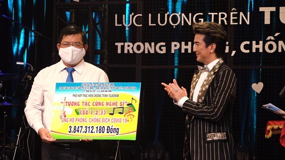 Pop star Dam Vinh Hung offers money to a representative of the Vietnam Fatherland Front's Ho Chi Minh City chapter.