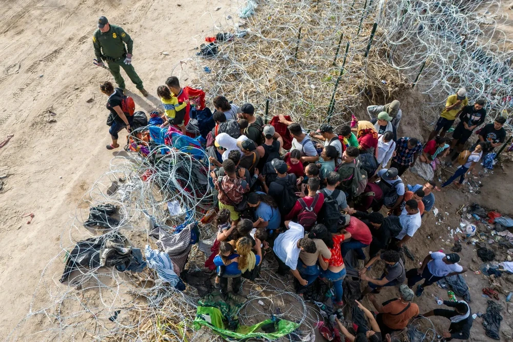 Người nhập cư tràn qua hàng rào an ninh ở biên giới bang Texas (Mỹ) - Mexico trong sự bất lực của nhân viên an ninh Mỹ. Ảnh: Newyorker