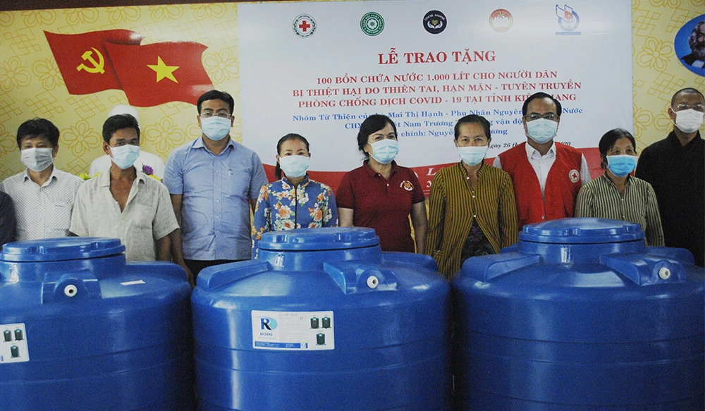 Phu nhân nguyên Chủ tịch nước Trương Tấn Sang (từ trái qua, người thứ 5) trao tặng 100 bồn chứa nước ngọt cho bà con nghèo tại xã Nam Thái A. Ảnh: TÍN HUY