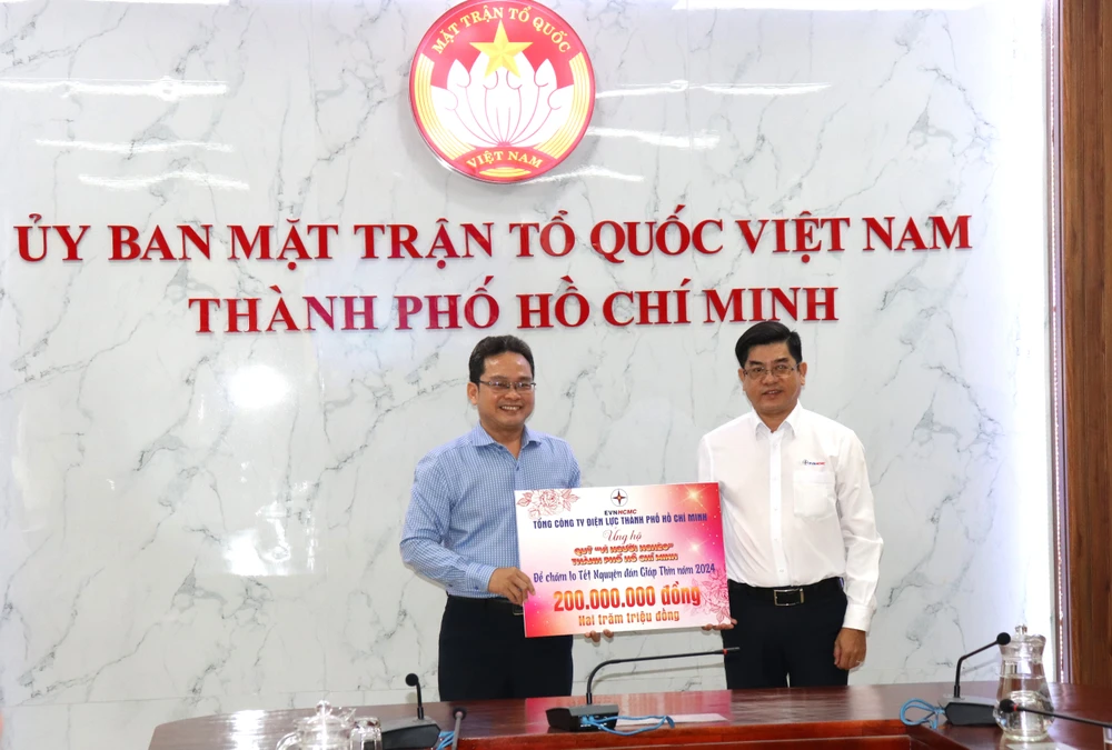 Phó Chủ tịch Ủy ban MTTQ Việt Nam TPHCM Phạm Minh Tuấn (trái) tiếp nhận 200 triệu đồng từ đại diện Tổng Công ty Điện lực TPHCM