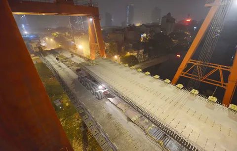 Việc thi công vẫn phải đảm bảo các phương tiện vẫn lưu thông bình thường bên dưới. Toàn cảnh khu vực lao dầm thuộc khu vực hồ Hào Nam. Phiến dầm sẽ được vận chuyển bằng xe chuyên chở đặc dụng tới vị trí lắp đặt. Cần cẩu chuyên dụng sẽ nâng phiến dầm lên trên mặt đường sắt. Dầm bê tông được cẩu ráp vào 2 trụ cầu giữa lòng hồ. Việc thi công vẫn phải đảm bảo các phương tiện vẫn lưu thông bình thường bên dưới. Toàn cảnh khu vực lao dầm thuộc khu vực hồ Hào Nam. Phiến dầm sẽ được vận chuyển bằng xe chuyên chở đặc dụng tới vị trí lắp đặt. Cần cẩu chuyên dụng sẽ nâng phiến dầm lên trên mặt đường sắt. Dầm bê tông được cẩu ráp vào 2 trụ cầu giữa lòng hồ.