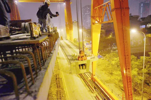 Việc thi công vẫn phải đảm bảo các phương tiện vẫn lưu thông bình thường bên dưới. Toàn cảnh khu vực lao dầm thuộc khu vực hồ Hào Nam. Phiến dầm sẽ được vận chuyển bằng xe chuyên chở đặc dụng tới vị trí lắp đặt. Cần cẩu chuyên dụng sẽ nâng phiến dầm lên trên mặt đường sắt. Dầm bê tông được cẩu ráp vào 2 trụ cầu giữa lòng hồ. Việc thi công vẫn phải đảm bảo các phương tiện vẫn lưu thông bình thường bên dưới. Toàn cảnh khu vực lao dầm thuộc khu vực hồ Hào Nam. Phiến dầm sẽ được vận chuyển bằng xe chuyên chở đặc dụng tới vị trí lắp đặt. Cần cẩu chuyên dụng sẽ nâng phiến dầm lên trên mặt đường sắt. Dầm bê tông được cẩu ráp vào 2 trụ cầu giữa lòng hồ.