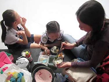 Một phụ huynh mang cơm cho con ăn ngay tại trường sau giờ học để con đi học thêm. Một phụ huynh mang cơm cho con ăn ngay tại trường sau giờ học để con đi học thêm.