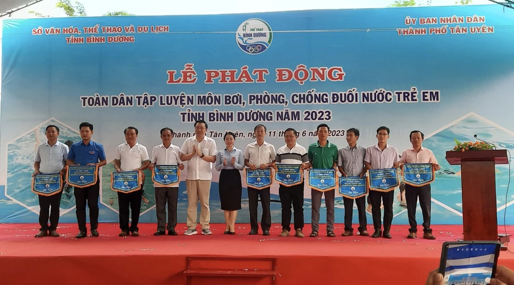 Ông Cao Văn Chóng - PGĐ Sở Văn hóa, Thể thao và Du lịch và bà Nguyễn Thị Kim Nguyên - Phó Chủ tịch UBND thành phố Tân Uyên tặng cờ lưu niệm cho các đơn vị tham dự Lễ Phát động